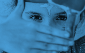 A blue-toned close-up of a child's eyes framed by their hands, used as a background banner.
