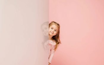 Happy kid, girl isolated on coral pink studio background.